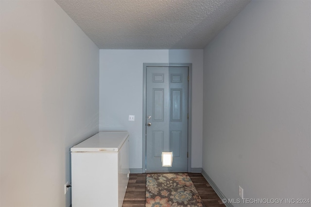 doorway to outside with dark wood-type flooring and a textured ceiling