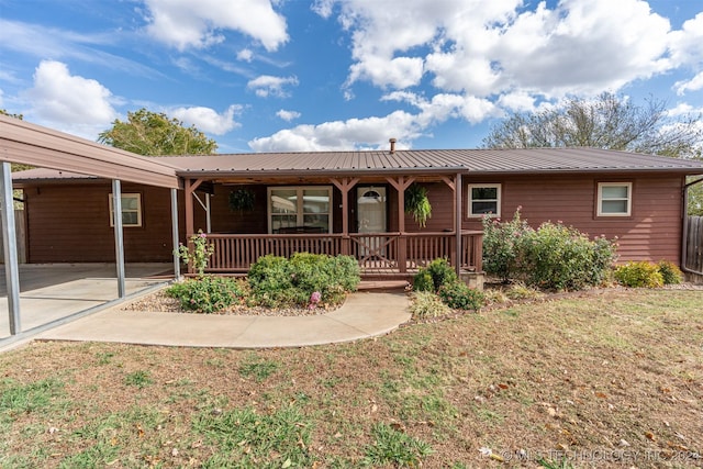 single story home featuring a porch, a carport, and a front lawn