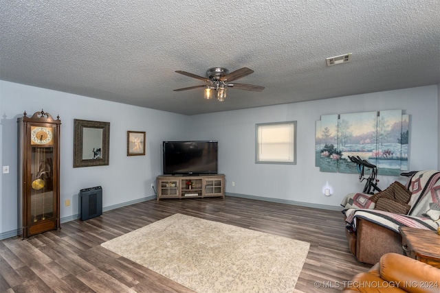 living room with a textured ceiling, ceiling fan, and dark wood-type flooring