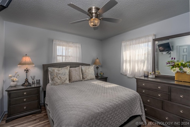 bedroom with a textured ceiling, ceiling fan, and dark wood-type flooring