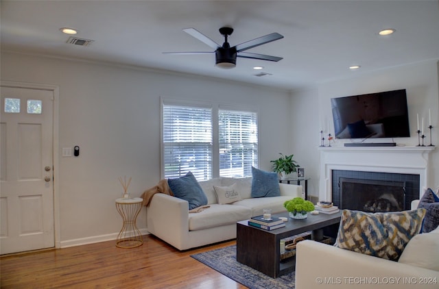 living room with a tile fireplace, ceiling fan, crown molding, and hardwood / wood-style flooring