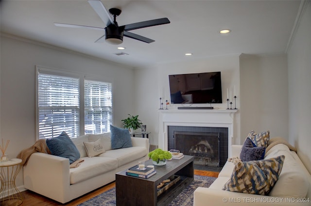 living room featuring a tile fireplace, ceiling fan, dark hardwood / wood-style flooring, and ornamental molding