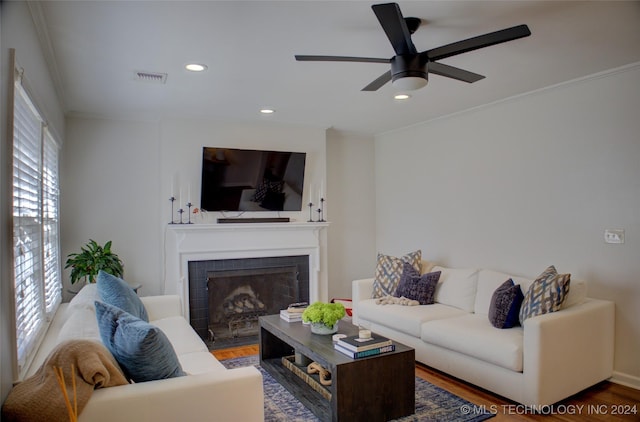 living room featuring a fireplace, hardwood / wood-style flooring, ceiling fan, and ornamental molding