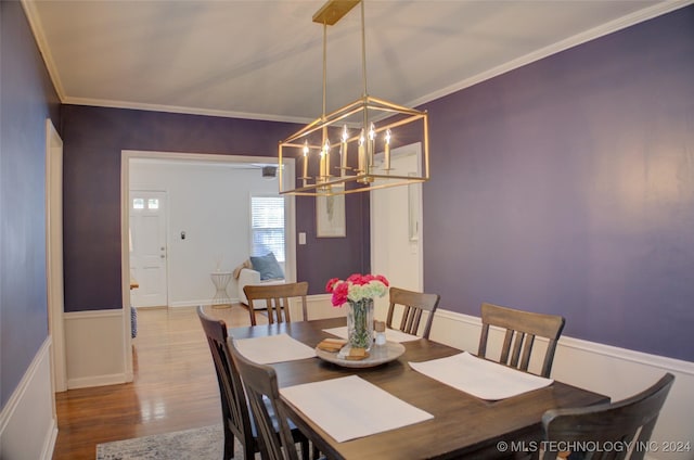 dining area featuring crown molding, hardwood / wood-style floors, and a chandelier