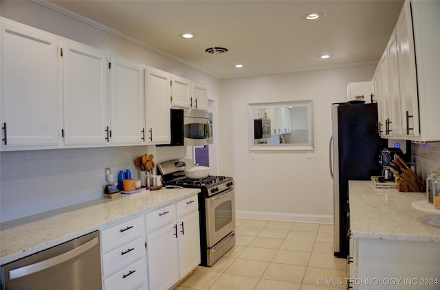 kitchen with white cabinets, appliances with stainless steel finishes, backsplash, and light tile patterned flooring