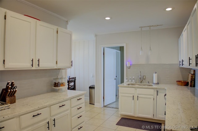 kitchen with white cabinetry, light stone countertops, sink, crown molding, and light tile patterned flooring