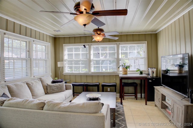 living room with wooden walls, ceiling fan, light tile patterned floors, and a wealth of natural light