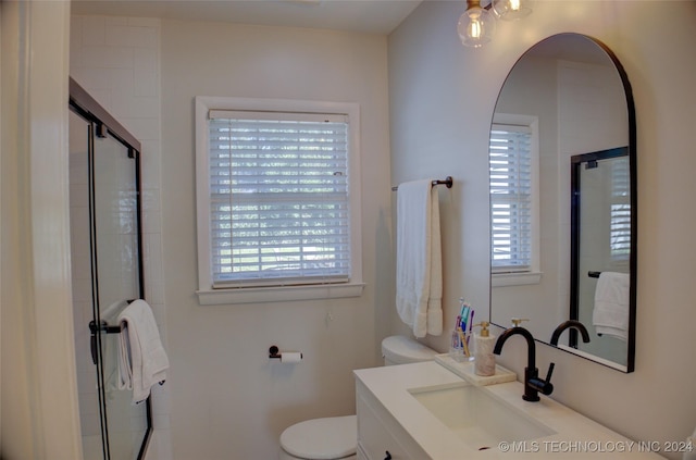 bathroom featuring vanity, a healthy amount of sunlight, a shower with shower door, and toilet