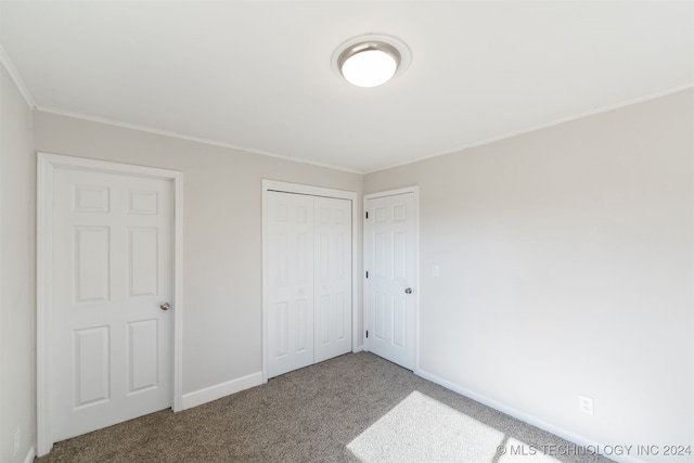 unfurnished bedroom featuring carpet flooring, ornamental molding, and a closet