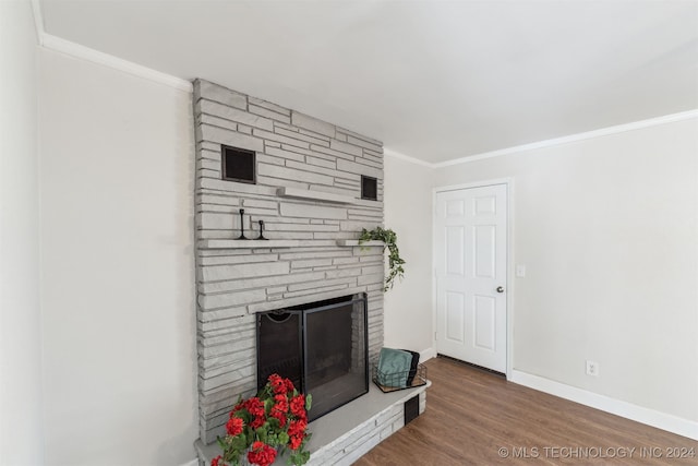 living room with hardwood / wood-style floors, a stone fireplace, and ornamental molding