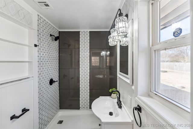 bathroom featuring a tile shower, plenty of natural light, vanity, and a notable chandelier