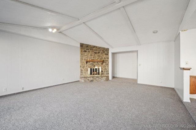 unfurnished living room featuring vaulted ceiling with beams, a stone fireplace, and carpet floors