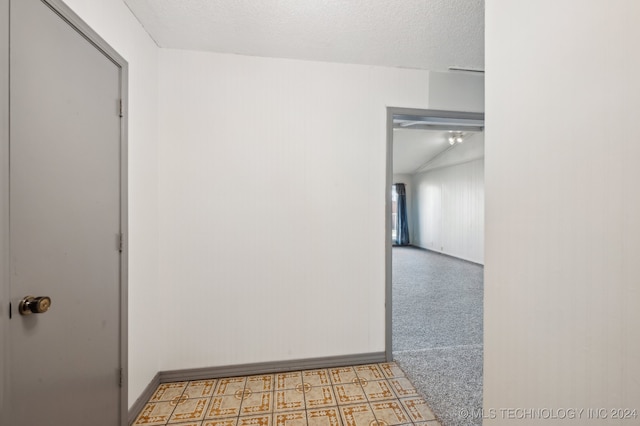 corridor featuring a textured ceiling and vaulted ceiling