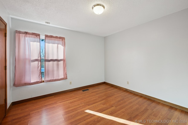 empty room featuring a textured ceiling and hardwood / wood-style flooring