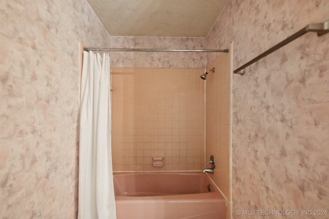 bathroom with shower / bath combination with curtain and a textured ceiling