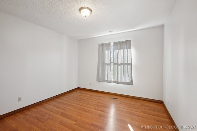 unfurnished room with light hardwood / wood-style floors and a textured ceiling