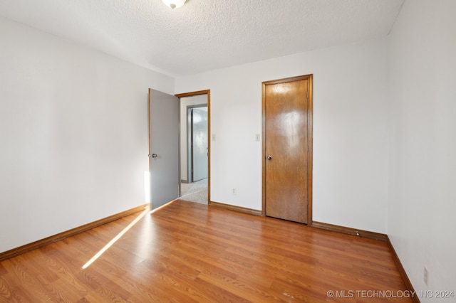 unfurnished bedroom with a textured ceiling and light wood-type flooring