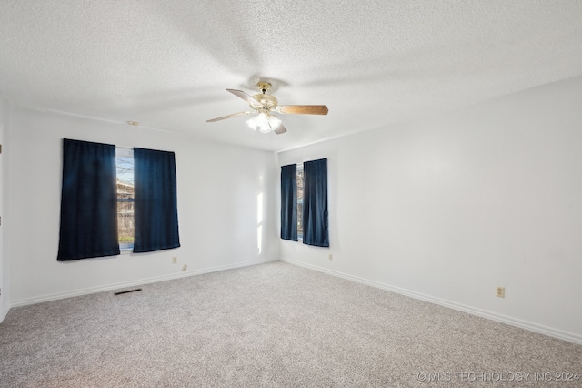 carpeted spare room featuring ceiling fan and a textured ceiling