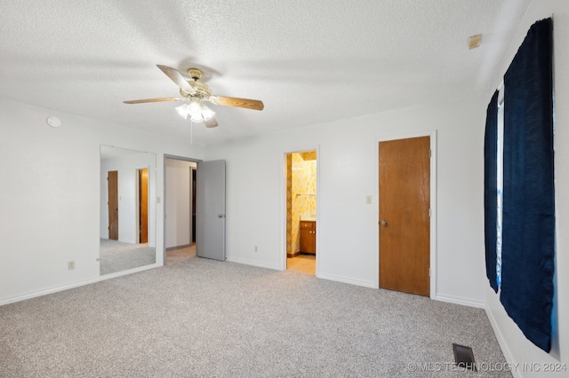 unfurnished bedroom featuring ensuite bath, ceiling fan, light carpet, and a textured ceiling