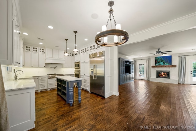 kitchen featuring pendant lighting, a center island, white cabinets, sink, and built in appliances