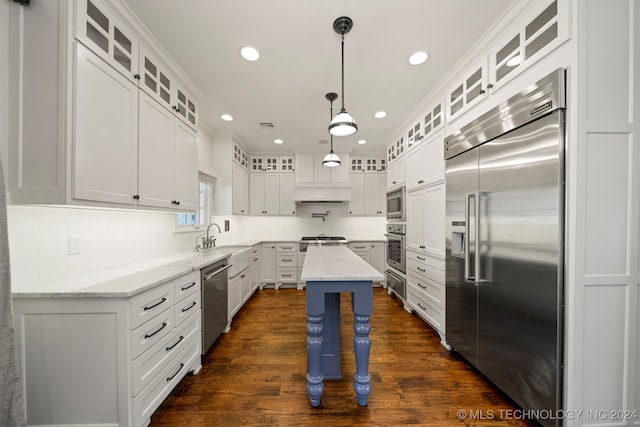 kitchen featuring light stone counters, a kitchen island, built in appliances, dark hardwood / wood-style floors, and white cabinetry