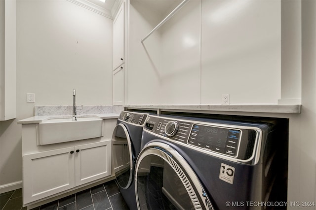 laundry room featuring washer and clothes dryer, sink, cabinets, and dark tile patterned flooring