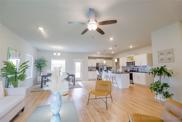 living room with light hardwood / wood-style flooring and ceiling fan with notable chandelier