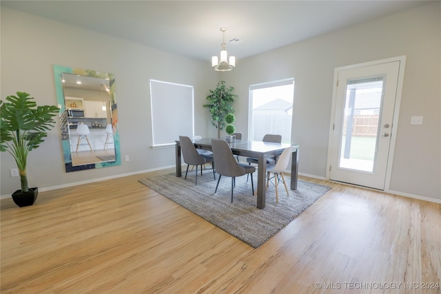 dining area with light hardwood / wood-style floors and an inviting chandelier