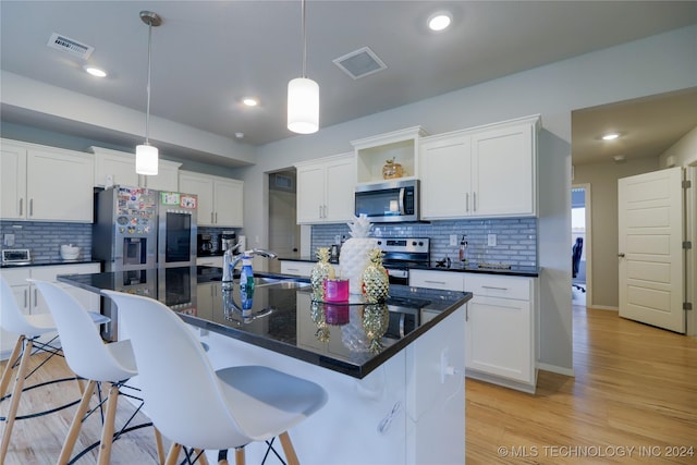 kitchen with stainless steel appliances, a kitchen island with sink, and tasteful backsplash