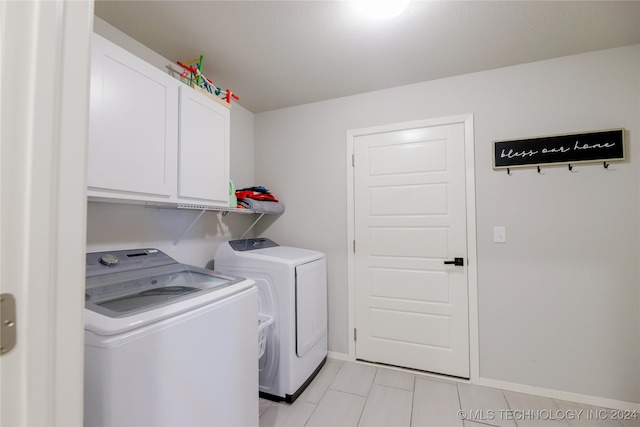 washroom featuring light tile patterned flooring, cabinets, and washing machine and clothes dryer