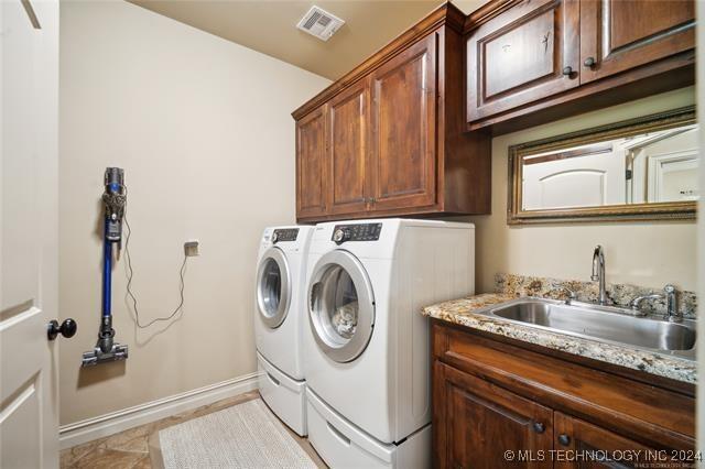 clothes washing area with cabinets, washing machine and dryer, and sink