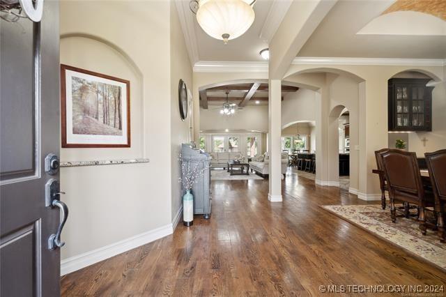 entrance foyer with beamed ceiling, dark hardwood / wood-style floors, a notable chandelier, and ornamental molding