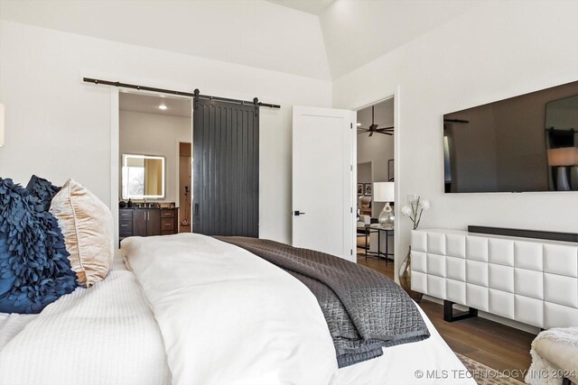 bedroom with a barn door and dark wood finished floors