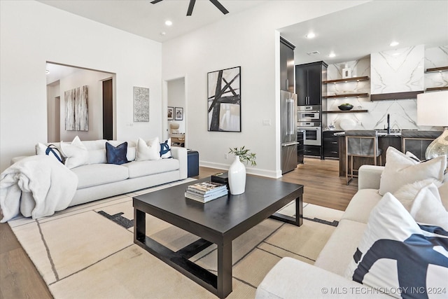 living area featuring a ceiling fan, recessed lighting, baseboards, and light wood finished floors