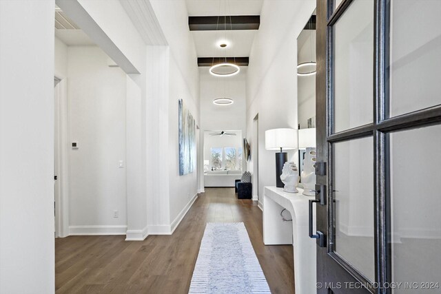 corridor featuring a high ceiling, dark wood-style flooring, visible vents, and baseboards