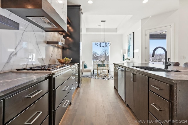 kitchen featuring dark brown cabinetry, a sink, hanging light fixtures, appliances with stainless steel finishes, and dark countertops