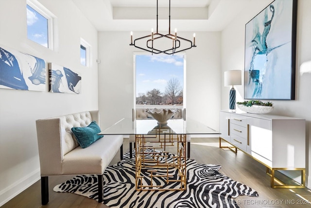 sitting room featuring light wood finished floors, baseboards, a raised ceiling, and a notable chandelier