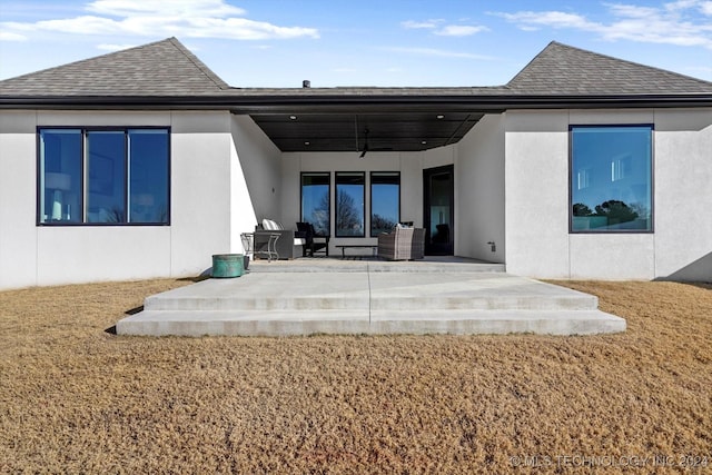 back of house with a shingled roof, a patio area, ceiling fan, and stucco siding