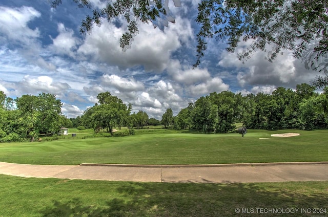 view of property's community with view of golf course and a lawn