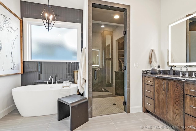 bathroom with a stall shower, baseboards, tile patterned flooring, vanity, and a freestanding tub