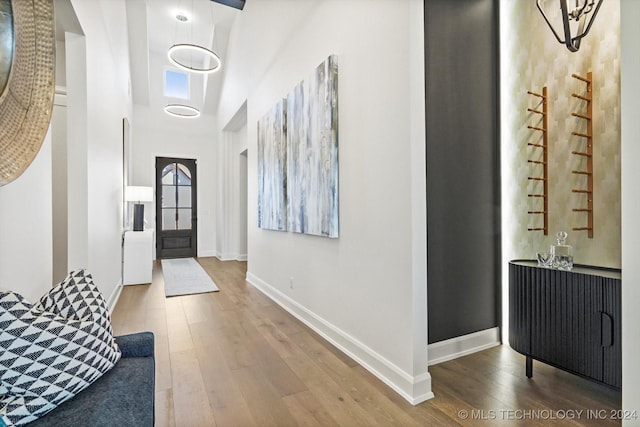 entryway with a towering ceiling, baseboards, and wood finished floors