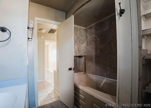 bathroom with tile patterned floors, sink, a textured ceiling, and tiled shower / bath