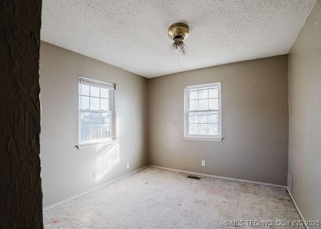 carpeted empty room with a textured ceiling