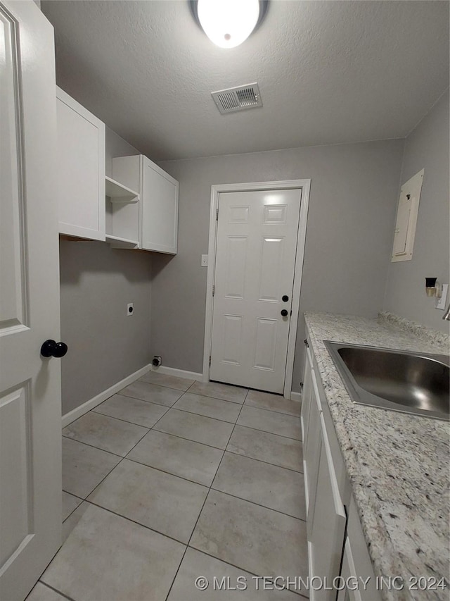 laundry room featuring hookup for an electric dryer, light tile patterned floors, a textured ceiling, and sink