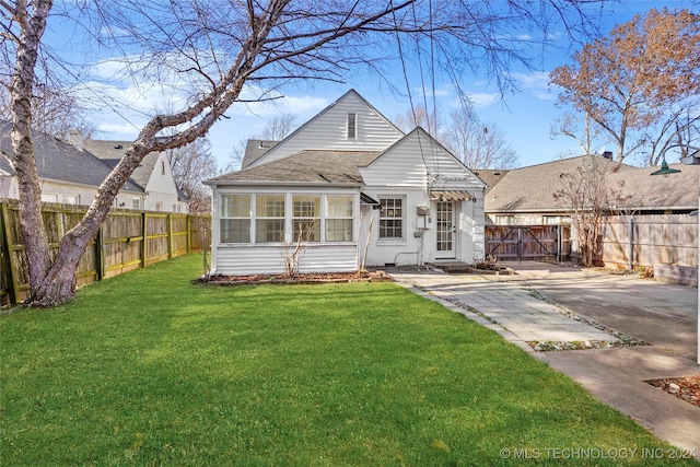 rear view of house with a yard and a sunroom