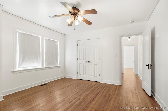 unfurnished bedroom with ceiling fan, light hardwood / wood-style flooring, and a closet