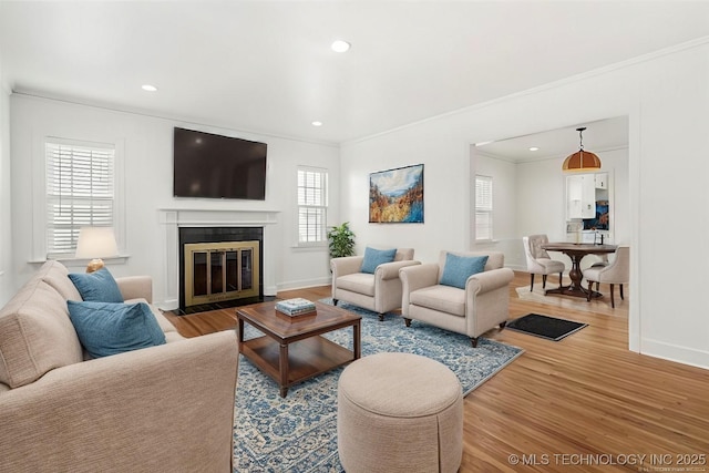 living room with a wealth of natural light, crown molding, and hardwood / wood-style flooring