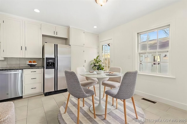 kitchen featuring tasteful backsplash, white cabinetry, light tile patterned floors, and appliances with stainless steel finishes