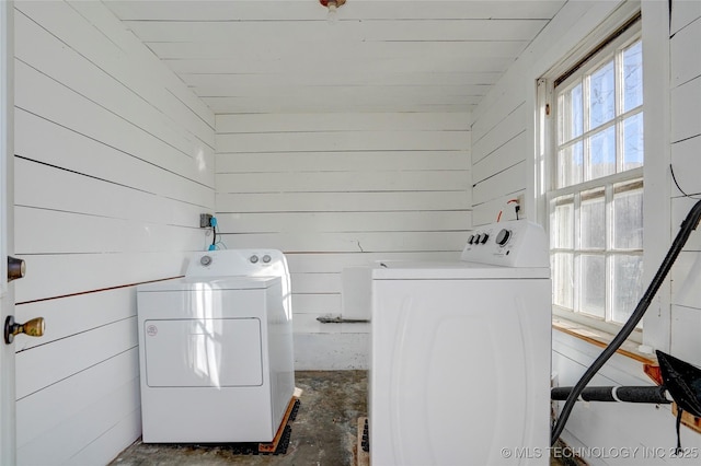 washroom featuring plenty of natural light, washing machine and dryer, and wooden walls