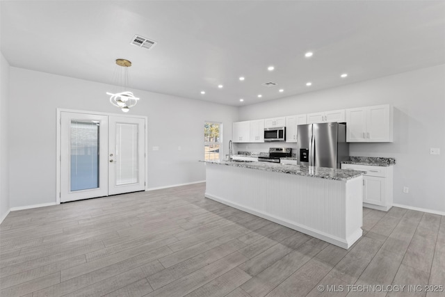 kitchen featuring hanging light fixtures, light hardwood / wood-style flooring, stainless steel appliances, and white cabinets